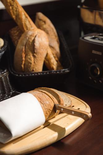 a loaf of bread on a table with a knife and a basket of bread at Boutique Hotel Saxonia in Karlovy Vary