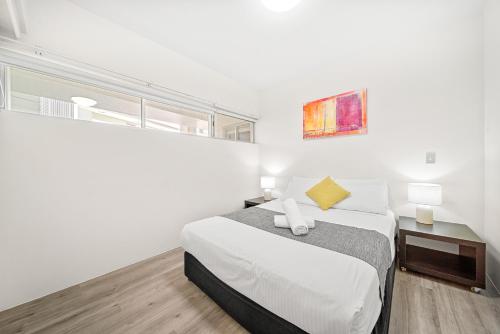 a white bedroom with a bed and a window at Oxygen Apartments in Brisbane