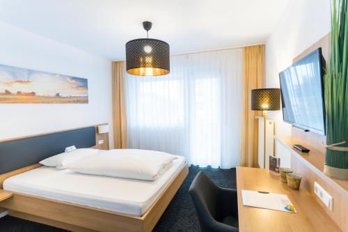 a hotel room with a bed and a desk at Hotel zur Sonne GmbH in Bodelshausen