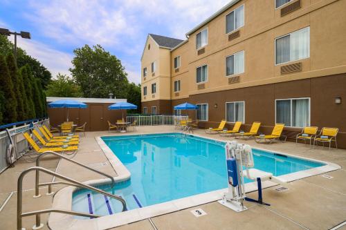 Fairfield Inn & Suites by Marriott Allentown Bethlehem/Lehigh Valley Airport في بيت لحم: مسبح وكراسي ومبنى