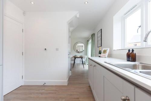 a kitchen with white cabinets and a sink and a table at Oxfordshire Living - The Vanderbilt - Woodstock in Woodstock