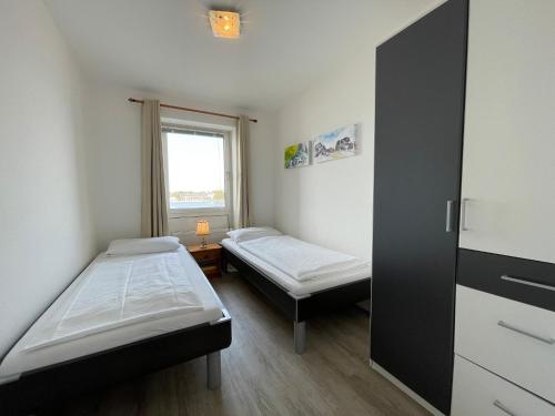 two beds in a small room with a window at Apartment 10 in Wilhelmshaven