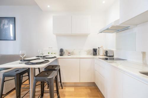 une cuisine avec des armoires blanches et une table avec des tabourets dans l'établissement Stylish 1-Bedroom Apartment in the City Center, à Cannes