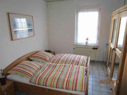 a bedroom with a bed with striped sheets and a window at Ferienwohnung Hartmann in Hermannsburg