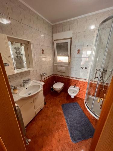 a bathroom with two sinks and a toilet and a shower at Apartments Gojević in Crikvenica