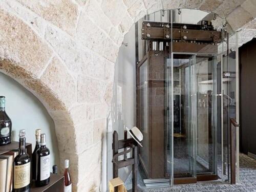 - une douche en verre dans une chambre avec des bouteilles de vin dans l'établissement Sei Stelle Mama, à Polignano a Mare