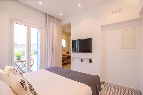 een witte slaapkamer met een bed en een televisie bij Galini Hotel in Mykonos-stad
