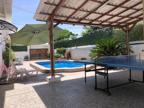 a patio with a table and an umbrella and a pool at Casa en Ballenita: Piscina, Vóley, BBQ y Mar Cerca in Ballenita