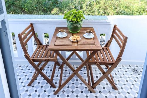 a wooden table and chairs on a balcony with a plant at Galini Hotel in Mýkonos City