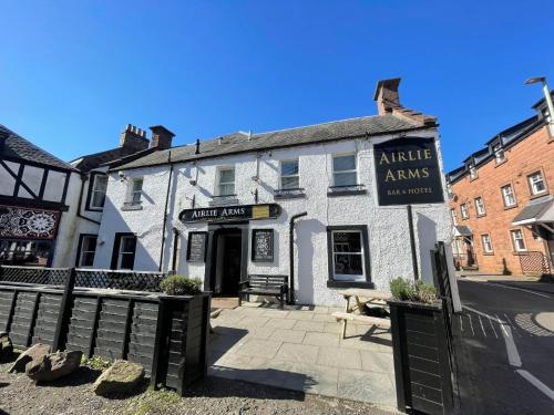 a white building with a sign on the front of it at Airlie Arms Hotel in Kirriemuir