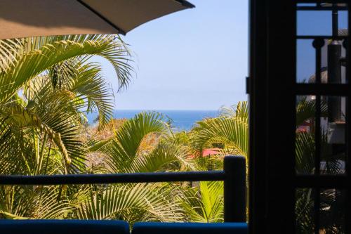 a window with a view of the ocean and palm trees at Villa Monte in Sayulita