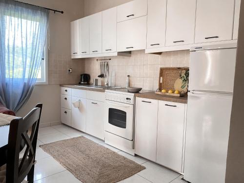 uma cozinha com armários brancos e um frigorífico branco em Kaloudis Studios & Apartments em Dassia