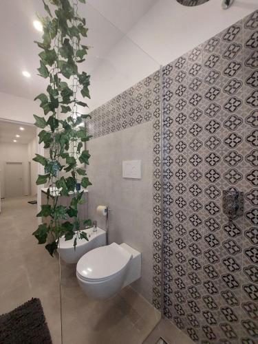 a bathroom with a toilet and a plant on the wall at Tropical Palm Villa in Monopoli