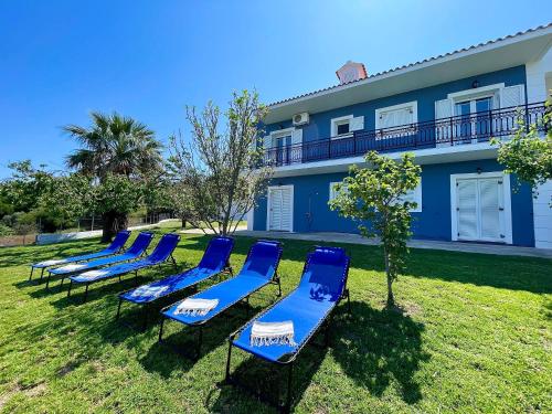 una fila de sillas de playa azules en el césped frente a un edificio en Villa Serenity Spilia 1st floor, en Argostoli