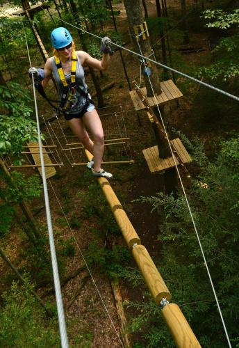 a woman walking on a rope bridge in the woods at Adventures on the Gorge in Fayetteville