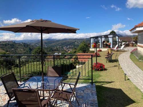 a table and chairs with an umbrella on a balcony at Pousada Ville Le Mont in Campos do Jordão