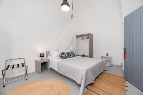 a white bedroom with a bed and a chair at 1812 Caves 'n Mansion in Karterados