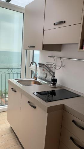 a kitchen with white cabinets and a sink and a window at Casa San Michele in Minori