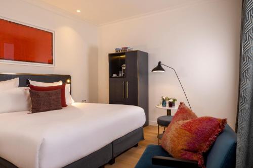 um quarto de hotel com uma cama e uma cadeira em Le 5 Particulier em Neuilly-sur-Seine