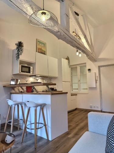 une cuisine avec des armoires blanches et des tabourets de bar dans l'établissement La Belle Jane - Hyper Centre - Fibre, à Albi