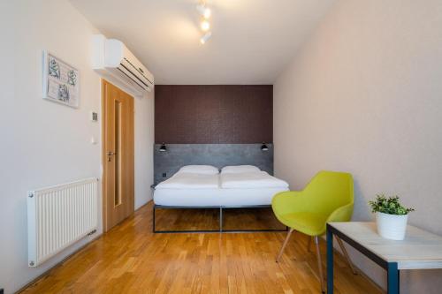 a bedroom with a bed and a green chair at EA ApartHotel Melantrich in Prague