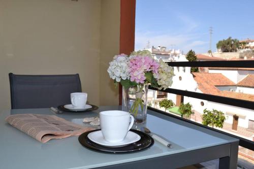 une table avec deux tasses et un vase de fleurs dans l'établissement Precioso apartamento en primera linea de playa, à Algarrobo-Costa