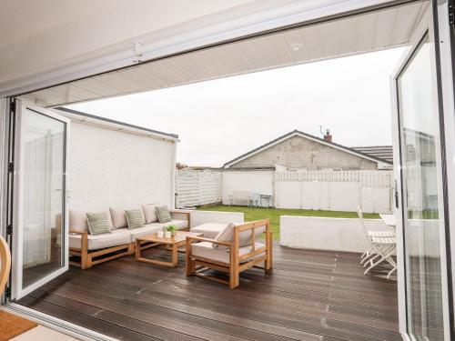 a sliding glass door opens up to a patio with a table and chairs at 31 Sisial Y Mor in Rhosneigr