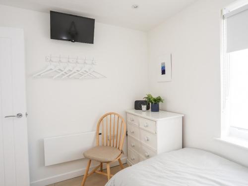 a bedroom with a bed and a chair and a dresser at 31 Sisial Y Mor in Rhosneigr