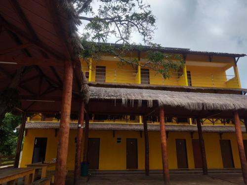 a yellow building with a straw roof at Tambazulik pousada in Maragogi