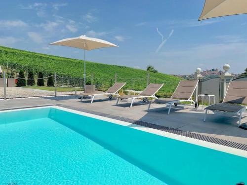 a swimming pool with chairs and an umbrella at Dimora San Carlo in Roddi