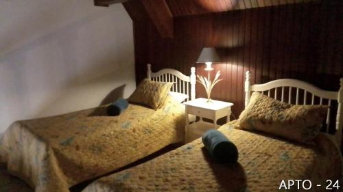 a bedroom with two twin beds and a lamp at Center Suiço Flats in Campos do Jordão