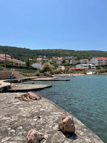 a body of water with rocks and buildings in the background at Apartaments Bee in Vinjerac