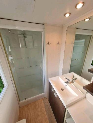 une salle de bain avec un lavabo et un grand miroir dans l'établissement Camping de l Orangerie de Lanniron Mobilhome Esprit Zen R26, à Quimper