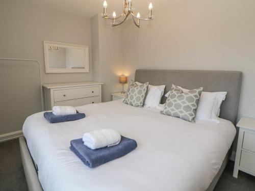 a bedroom with a large white bed with blue towels on it at Wayland House in Bakewell