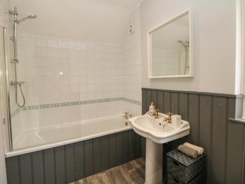a bathroom with a tub and a sink and a mirror at Wayland House in Bakewell