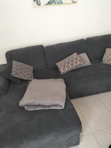 - un canapé noir avec des oreillers dans le salon dans l'établissement Hébergement 24h le mans, au Mans