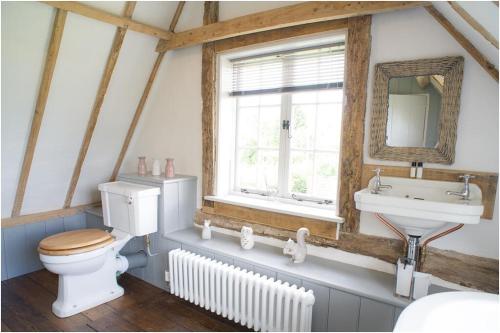 a bathroom with a toilet and a sink and a window at The Cottage, High Ash Farm in Peasenhall
