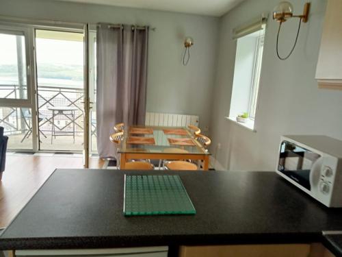 a kitchen and dining room with a table and a microwave at Sunnyside View Apartment -modern & cosy apartment with magnificent views to match in Youghal