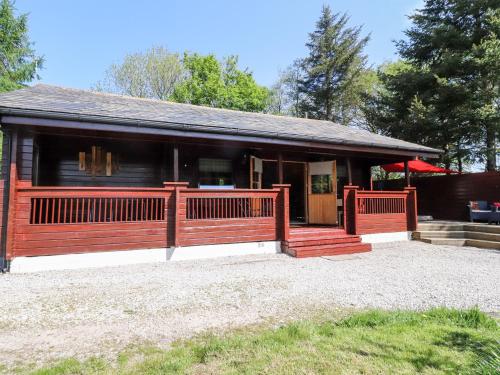 a small house with a porch and a fence at Gisburn Forest Lodge in Skipton