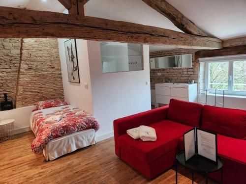 - un salon avec un canapé rouge et un lit dans l'établissement Maison Laurenza La grande suite 1760, à Saint-Jean-de-Liversay