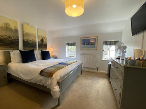 a bedroom with a large bed with blue pillows at Kings Head Low House in Laxfield
