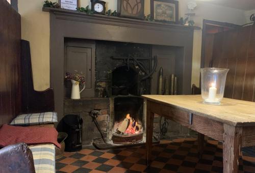 a fireplace in a living room with a fire in it at Kings Head Low House in Laxfield