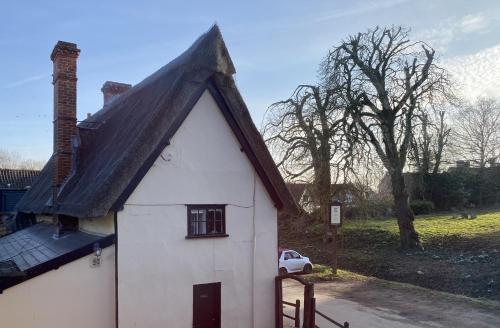 a white house with a black roof and a car at Kings Head Low House in Laxfield