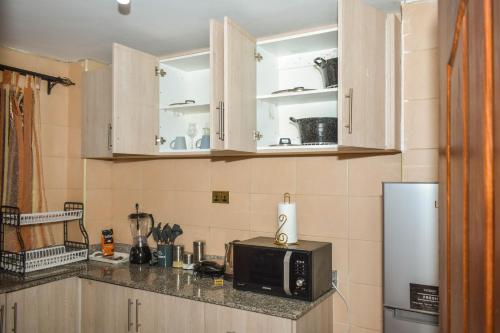 - une cuisine avec des placards en bois et un four micro-ondes dans l'établissement Lux Suites 2 Bedroom Diamonte Apartment Ngara, à Nairobi