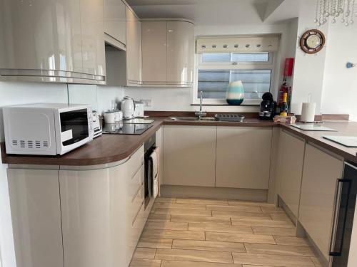 a kitchen with white cabinets and a microwave on a counter at Coastview Bungalow in Pevensey