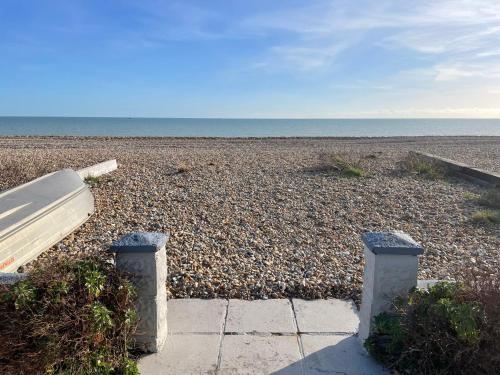 a bench on a beach with the ocean in the background at Coastview Bungalow in Pevensey