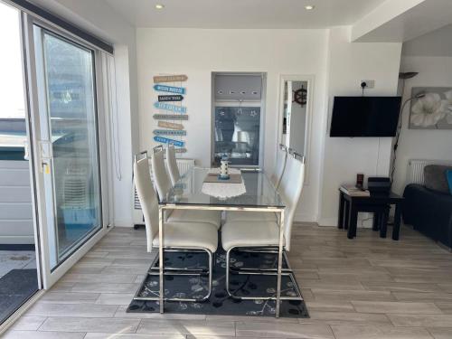 a dining room with a glass table and white chairs at Coastview Bungalow in Pevensey
