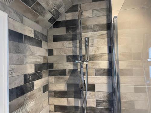 a bathroom with a shower with wood tiles on the wall at Coastview Bungalow in Pevensey