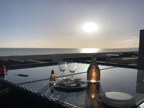 a table with two wine glasses and a bottle at Luxury Beachfront The Cozy Clam in Pevensey