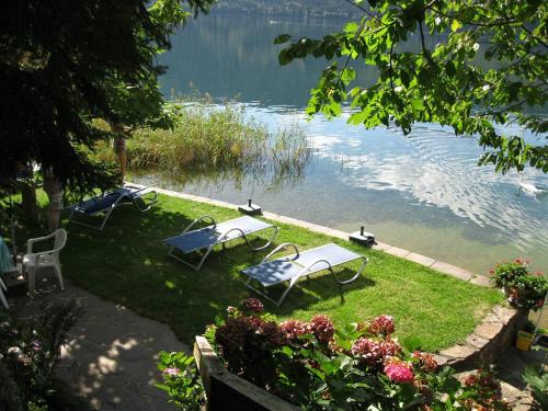 three picnic tables on the grass near the water at Seefels Appartements in Döbriach
